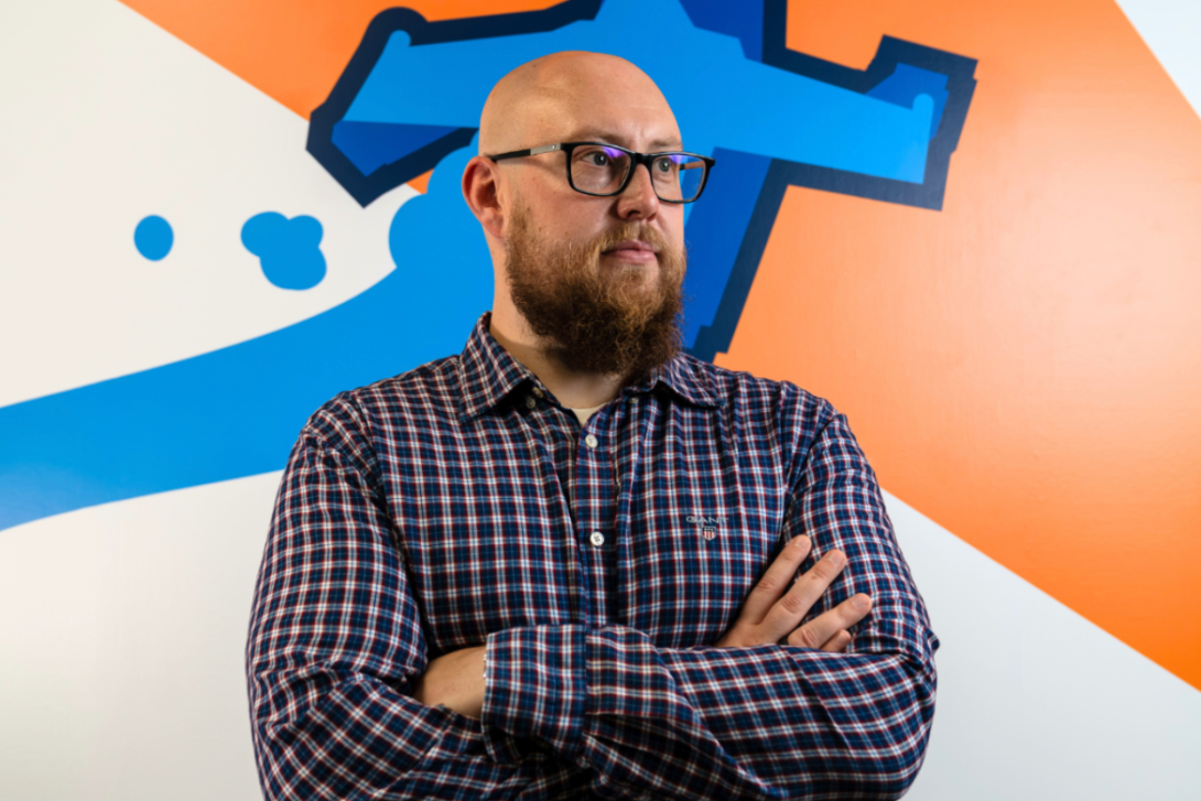 Our VP of mobile games stands confidently, arms crossed, facing the camera against an orange and white background.